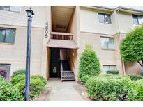 The exterior shows the front entrance to the condo with brick and surrounding green bushes at 4806 Spring Lake Dr # D, Charlotte, NC 28212