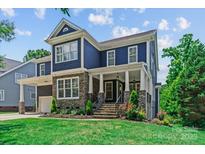 Charming two-story home with blue siding, stone accents, a covered porch, and manicured landscaping at 615 N Oak Dr, Huntersville, NC 28078