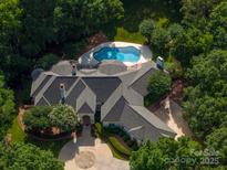 Stunning aerial view of the luxury home with mature trees surrounding a backyard pool area at 7912 Baltusrol Ln, Charlotte, NC 28210