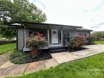 Charming home featuring a covered porch and landscaping with red roses at 111 Rose St, Mount Holly, NC 28120