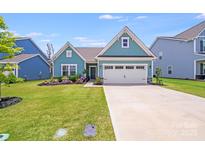 Charming blue two-story home with a well-manicured lawn and two car garage at 1391 Links Crossing Dr, Monroe, NC 28112