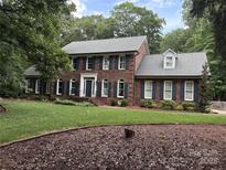 Elegant two-story brick home featuring a manicured lawn and black shutters for a classic, sophisticated look at 1545 Chadmore Nw Ln, Concord, NC 28027