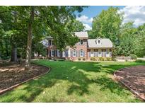 Charming brick home with a lush lawn, complemented by a well-maintained landscape and mature trees at 1545 Chadmore Nw Ln, Concord, NC 28027