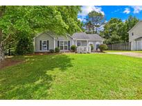 Charming single story home featuring a lush green lawn, complemented by mature trees, and black shutters at 2490 Hawk Ridge Dr, Gastonia, NC 28056