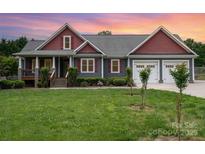 Charming gray two-story home features a manicured front lawn, covered porch, and attached two-car garage at 8993 Plank Rd, Norwood, NC 28128