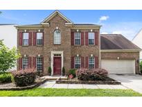 Charming two-story brick home with a well-manicured lawn and inviting red door and red shutters at 11834 Planters Estates Dr, Charlotte, NC 28278