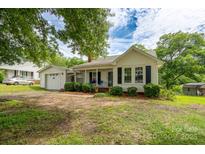 Charming single-story home featuring a quaint front porch and an attached garage on a sunny day at 357 N Main St, Mount Pleasant, NC 28124