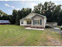 Charming home featuring a lush lawn, complemented by mature trees and a rustic outbuilding in the background at 40287 Palmerville Rd, New London, NC 28127