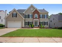 Charming two-story home with a well-manicured lawn, brick accents, black shutters, and attached garage at 5005 Chestnut Knoll Ln, Charlotte, NC 28269