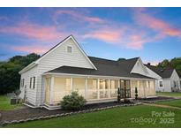 Charming exterior view of home with front porch, manicured lawn, and colorful sky at 515 N Main Gq St, Granite Quarry, NC 28146
