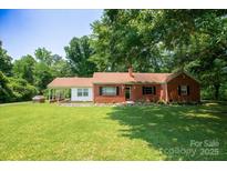 Charming red brick home with a spacious front yard, mature trees, and covered entrance at 7016 Tirzah Rd, Waxhaw, NC 28173