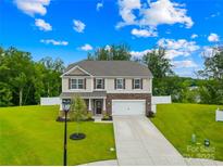 Charming two-story home with stone accents, a well-manicured lawn and a long driveway to the two-car garage at 132 Sycamore Crossing Ct, Locust, NC 28097