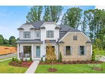 Inviting two-story home showcases a stone facade, light blue front door, manicured lawn, and well-maintained flower beds at 14011 Camden Close Cir # 25, Huntersville, NC 28078