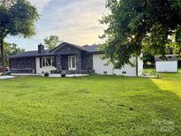 Charming one-story home featuring a stone facade, manicured lawn, and mature trees at 21035 Coley Store Rd, Locust, NC 28097