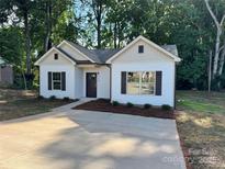 Charming single-story home with white siding, dark shutters, and a concrete driveway at 219 Pine St, Rockwell, NC 28138