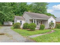 Quaint single-story home featuring neutral siding, mature landscaping, and a detached garage at 2722 Eastway Dr, Charlotte, NC 28205