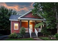 Charming red home with a welcoming front porch and landscaped garden at sunset at 3519 Card St, Charlotte, NC 28205