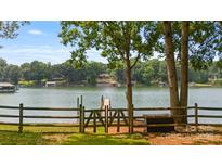 Picturesque lake view with a wooden fence and gate, inviting you to explore the serene waterfront property at 6836 Summer Hill Dr, Denver, NC 28037