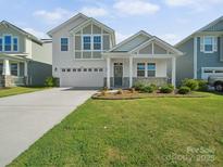 Charming two-story home with a well-manicured lawn, stone accents, and inviting front porch at 1207 Laggan Ln, Indian Trail, NC 28079