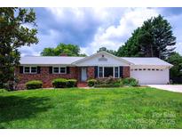 Charming brick home featuring a well-manicured lawn, landscaping, and an attached two-car garage at 1216 Manchester Ln, Charlotte, NC 28227
