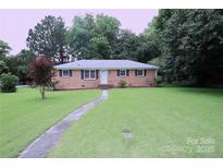 Charming brick home featuring a well-manicured lawn and inviting walkway at 1227 Flowe Dr, Matthews, NC 28104