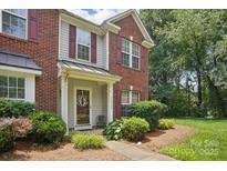 Charming townhome entrance with brick facade, decorative door, and manicured landscaping at 12342 Swan Wings Pl, Huntersville, NC 28078