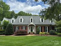 Charming, traditional red brick home with black shutters, dormer windows and a meticulously landscaped front yard at 1240 Fawn Ridge Nw Rd, Concord, NC 28027