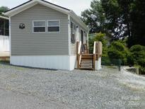 Charming home featuring gray siding, a white base, and a small porch with wooden stairs at 166 Eagle Dr, New London, NC 28127