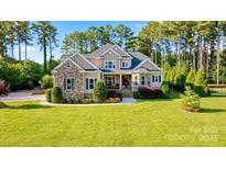 Charming two-story home featuring a lush green lawn, stone accents, and inviting curb appeal surrounded by mature trees at 230 Washam Rd, Mooresville, NC 28117