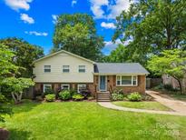 Charming two-story home featuring a well-manicured lawn, brick accents, and lush landscaping under a sunny sky at 2919 Dunaire Dr, Charlotte, NC 28205