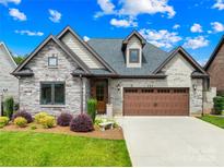 Beautifully landscaped, two-story home featuring a stone facade, brick accents, and a two-car garage at 6107 Gold Springs Way, Denver, NC 28037