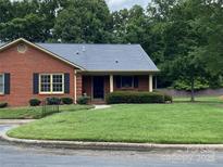 Charming brick home featuring a lush green lawn and mature trees in a peaceful neighborhood at 8421 Coulwood Oak Ln, Charlotte, NC 28214