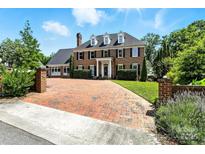 Stately brick home with mature landscaping, brick driveway, and classic black shutters under a sunny sky at 1009 13Th Avenue Nw Pl # 19, Hickory, NC 28601