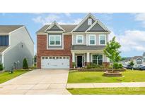 Charming two-story home with a brick and gray facade, well-manicured lawn, and a two-car garage at 1115 Macallum Nw Dr, Concord, NC 28027