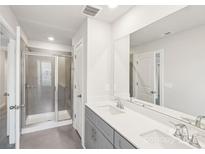 Bright bathroom featuring a glass shower, a dual sink vanity with gray cabinets, and large mirror at 135 Utility Ln, Mooresville, NC 28117