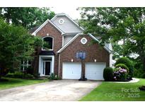Charming brick two-story home featuring a two-car garage, landscaped yard, and inviting entrance at 13934 Kings Carriage Ln, Charlotte, NC 28278