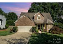 Charming brick home with manicured lawn, mature trees, and a two-car garage at 19509 Trintella Ln, Cornelius, NC 28031