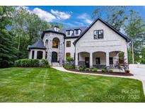 Stunning stone and brick home featuring a manicured lawn and arched entryway at 6327 Fox Tail Ln, Davidson, NC 28036
