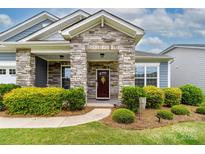 Inviting front door with stone accents and a charming wreath, surrounded by manicured landscaping at 732 Wood Lily Dr, Belmont, NC 28012