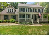 Charming two-story home with covered porch, blue shutters, landscaped yard, and American flag at 8300 Quarters Ln, Mint Hill, NC 28227