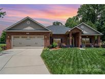 Charming single-story brick home with a two-car garage, manicured lawn, and inviting front porch at 101 Harvest Farm Ct, Mount Holly, NC 28120