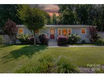 Charming single story home featuring a brick facade, well-manicured lawn, mature trees and a vibrant landscape at 1114 Urban Pl, Charlotte, NC 28209