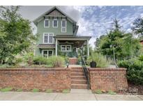 Charming two-story home with a brick facade, covered porch, and beautifully landscaped front yard at 1427 Main St, Charlotte, NC 28204