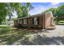 Charming brick home featuring black shutters, landscaped yard, and a gravel driveway, shaded by mature trees at 1787 Eastover Dr, Mount Pleasant, NC 28124