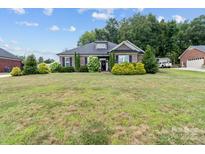 Charming single-story brick home with a large front lawn and well-maintained landscaping and black shutters at 203 Poplins Grove Church Rd, Albemarle, NC 28001