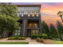 Modern townhome with brick facade, balcony, landscaped front yard, and a vibrant sunset backdrop at 2523 Irwin Stream Rd, Charlotte, NC 28208