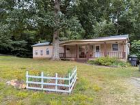 Charming single-story home featuring a welcoming front porch and a garden, nestled amongst mature trees at 370 Miracle Dr, Salisbury, NC 28146