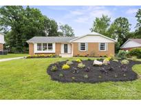 Charming brick home with a well-manicured front yard featuring lush landscaping and a healthy green lawn at 5817 Red Carriage Ln, Charlotte, NC 28212