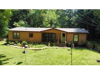Charming, wood-sided home with a screened-in porch, surrounded by lush greenery and a well-manicured lawn at 5832 Thompson Rd, Charlotte, NC 28216