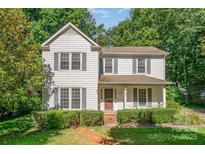 Charming two-story home features gray shutters, a covered porch, and a neatly landscaped front yard at 9701 Kent Village Dr, Charlotte, NC 28269